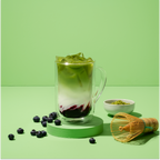 blueberry matcha  iced latte surrounded by matcha tools and berries